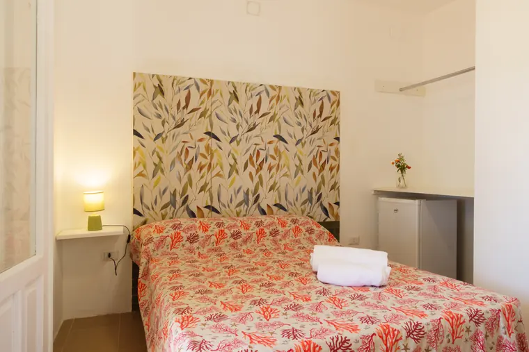 Camera matrimoniale del bungalow, con testiera decorata e asciugamani sul letto