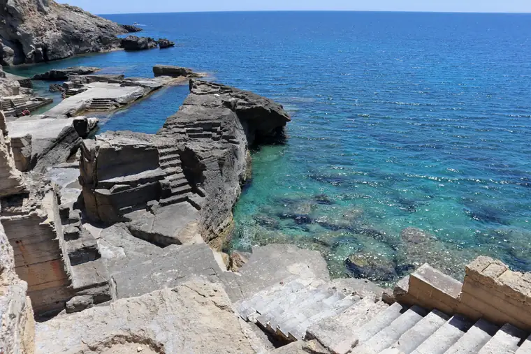 Gli scogli piatti e le scalette di pietra di Località Fontanelle sul mare blu.