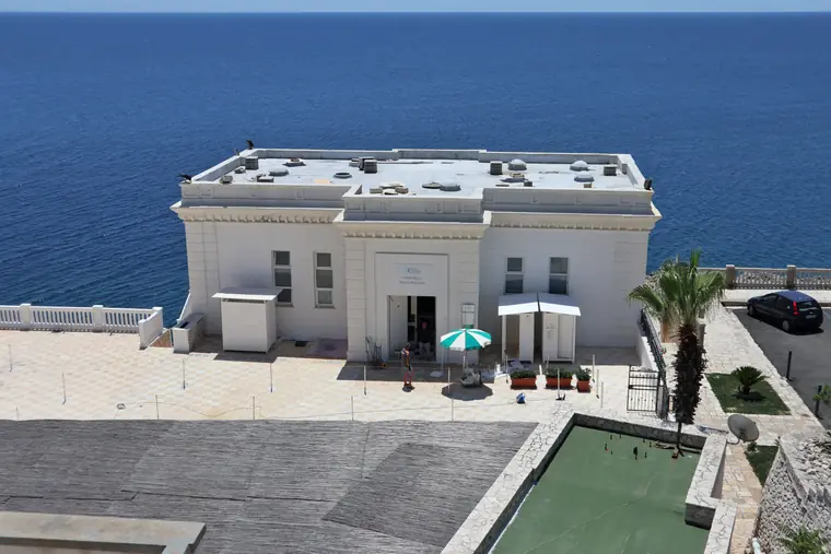 L'edificio bianco della Piscina Sulfurea affacciato sul mare aperto.