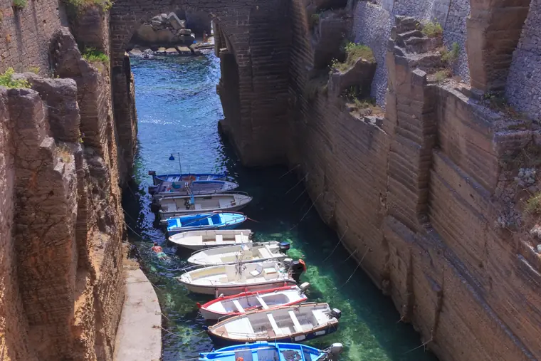 Le barche dei pescatori ormeggiate nel canale di Porto Vergine, fra pareti di roccia scavate a gradoni.