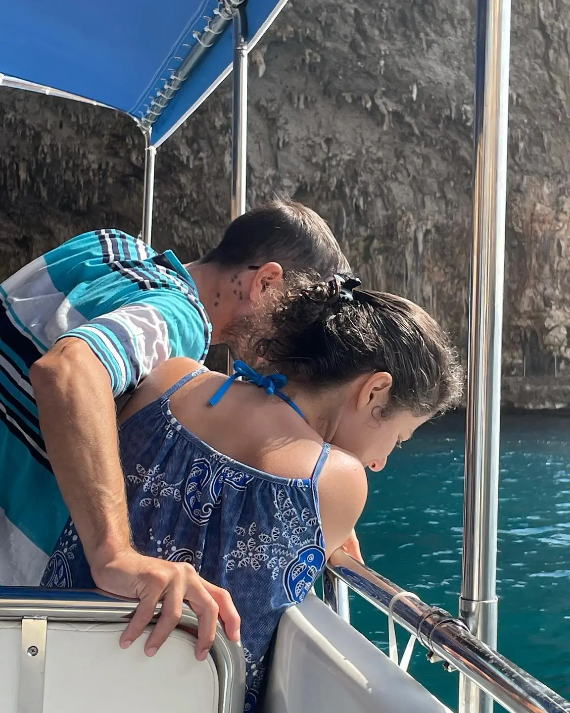 Due passeggeri affacciati dalla barca guardano l'acqua turchese sotto la scogliera