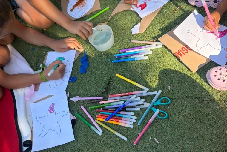Bambini del miniclub che disegnano sul prato con i pennarelli