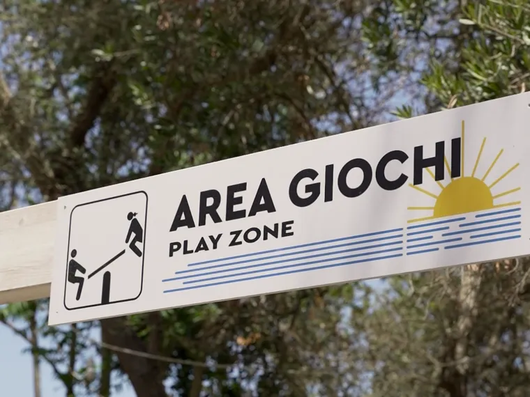 Il cartello dell'area giochi tra gli ulivi