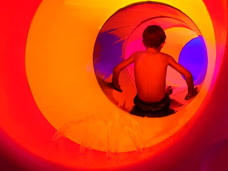 Un bambino dentro il tubo colorato dello scivolo